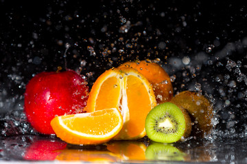 Multivitamin in water spalsh and drops on black background. Fresh fruits in water spray, multi fruits.