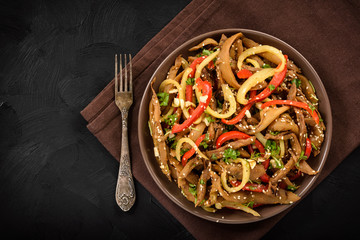 Asian style eggplant spicy salad on black background. Top view.