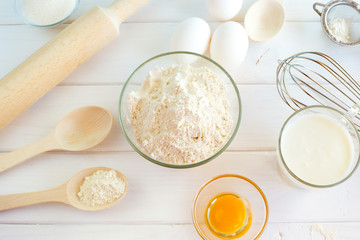 
Ingredients for the preparation of dough for biscuits. Flour and eggs on a white wooden background.