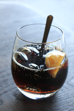 Glass of cola with ice cubes and slices of lemon