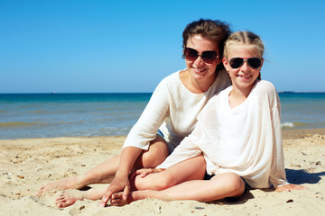 Fototapeta premium Portrait of a happy parent and child resting on the beach