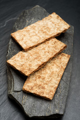 Three tasty rye crisp bread slices without topping on black stone. Crisp bread is part of the traditional Nordic culinary culture.