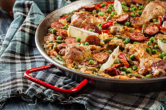 Traditional paella with chicken legs, sausage chorizo and vegetables served in paellera