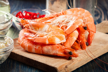 Selection of shrimp ready for frying with onion, garlic, chili and lime on cutting board