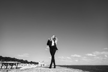 The stylish girl stands on the pier near sea