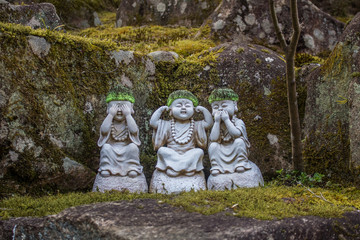 Jizo Bosatsu  statues with knitted caps illustrating see no evil hear no evil speak no evil on moss...