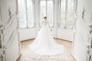 The charming bride stands near windows