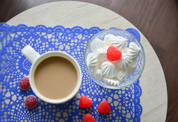 coffee with milk in white Cup and meringue on a round table