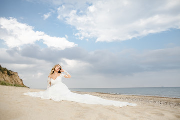 Fototapeta na wymiar The beautiful bride sitting on the sand