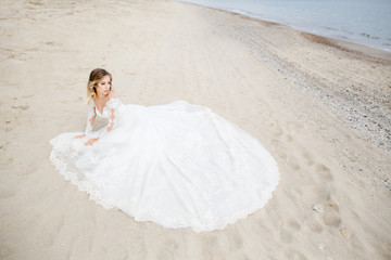Fototapeta na wymiar The beautiful bride sitting on the sand
