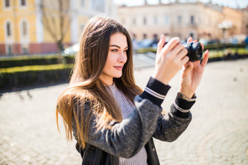 Outdoor smiling lifestyle portrait of pretty young woman having fun in the city in Europe with camera travel photo of photographer making pictures