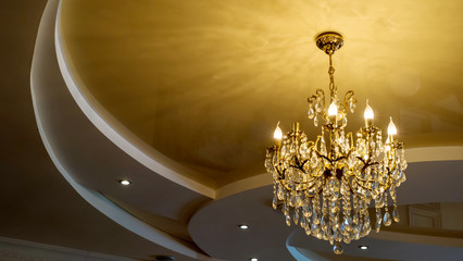 Elegant golden crystal chandelier on a stretch ceiling