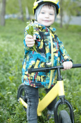 A child holds out a bouquet of flowers, sits on a bicycle
