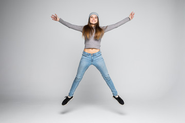Obraz premium Urocza szczęśliwa kobieta skacze z radości na szarym tle
