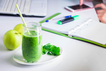 Workplace working table with laptop, computer, notebook, phone mobile smart phone, pen, marker. Healthy Drink Smoothie from Green Spinach and Apples