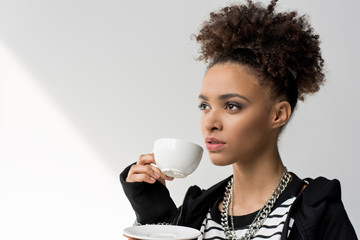portrait of young african american girl holding cup of tea and looking away