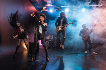 Young multiethnic rock and roll band performing hard rock music on stage