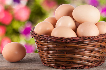 eggs on a wooden table in a wicker basket with blurred garden background