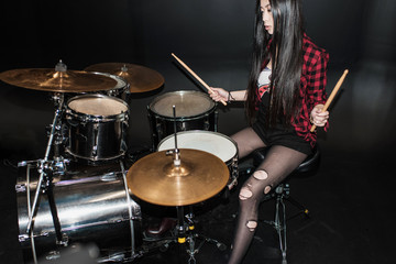 Rock and roll girl playing hard rock music with drums set