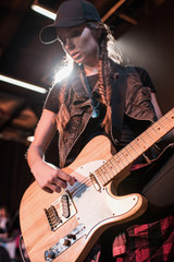 Obraz premium Young beautiful rock and roll girl playing bass guitar on stage