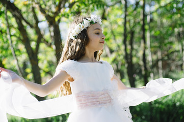 Attractive blond girl in forest dressed in communion