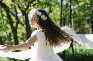 Attractive blond girl in forest dressed in communion