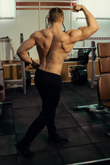 Naklejka premium Muscular athlete, bodybuilder with a naked torso posing in the gym. Hardened muscles, biceps