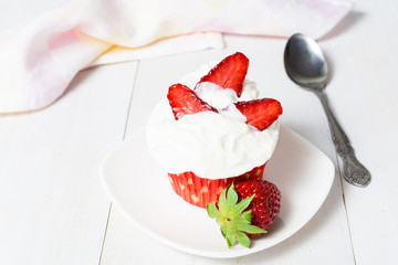 Cupcake in red paper form with whipped cream and strawberry