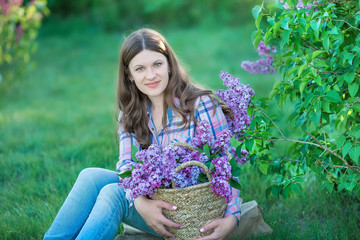 Beautiful woman enjoying lilac garden, young woman with flowers in green park. girl tearing the lilac in the garden