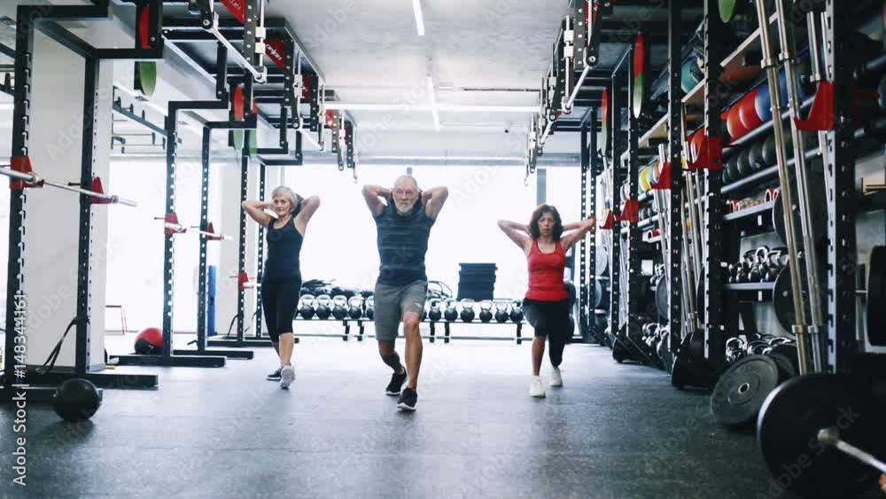 Wall mural Fit seniors in gym working out, doing lunges