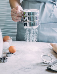 Woman Chef sifts flour, knead the dough. Bakery or Baking Concept. Ingredients for dough