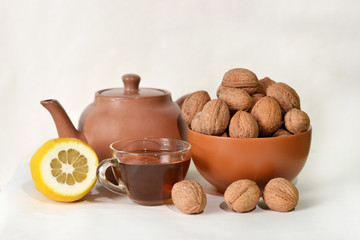 Tea with a lemon and nuts on a white background