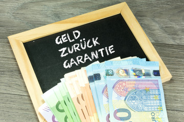 Geld und eine Kreidetafel mit dem Slogan Geld Zurück Garantie