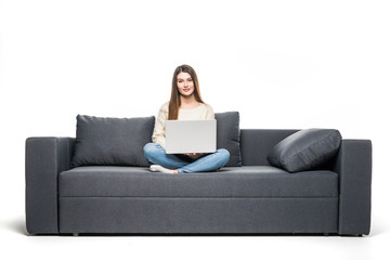 Fototapeta na wymiar Young woman lying on couch and using laptop at home