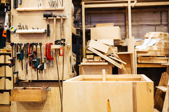 Background image of empty carpenters workshop: various woodworking tools, wooden boards and parts of furniture in factory