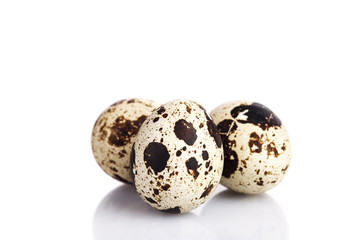 Three quail eggs over white background