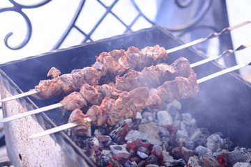 Marinated meat roasted on the coals in the grill, shish kebab on skewers. Spring weekend, picnic