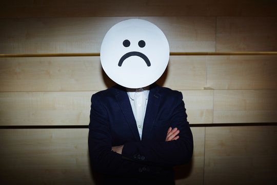 Upset Businessman In White Shirt And Suit Covered His Face With Sad Mask While Standing With Arms Crossed Against Wooden Wall