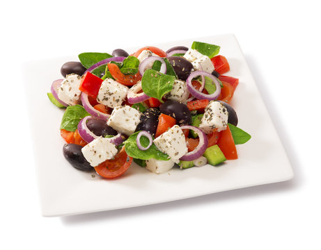 Greek salad in a square plate isolated on white