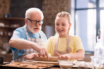 grandfather and granddaughter kneading dough