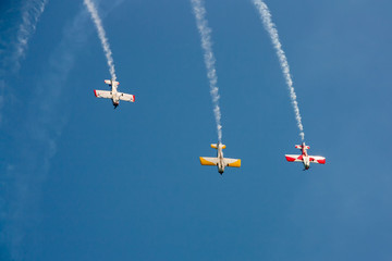 Acrobatic performance of three sports airplanes with the release of smoke