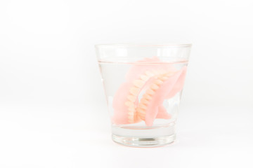 Complete denture is cleaned in a glass of water. proper hygiene.