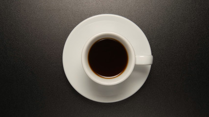 Obraz na płótnie Canvas White cup with coffee drink on black table