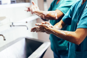 Couple of Surgeons Washing Hands Before Operating. - obrazy, fototapety, plakaty
