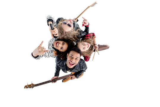 Overhead view of happy young rock and roll band posing with instruments isolated on white