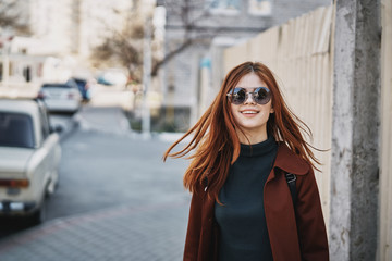 Obraz premium beautiful woman in glasses walking around the city, a brick wall