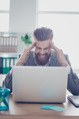 Overworked stressed businessman is having headache and thinking how to end project. He has stylish beard and hairstyle