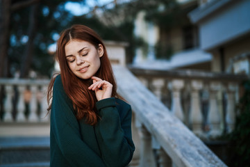 Obraz premium an elegant lady in a green sweater descends the steps holding onto the railing