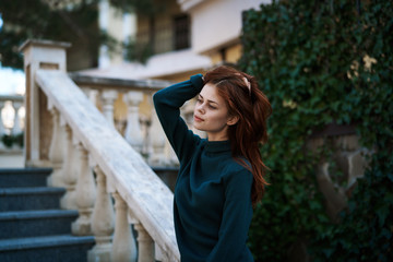 an elegant lady in a green sweater descends the steps holding onto the railing