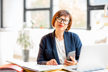 Senior businesswoman working with documents and laptop at the bright modern office interior
